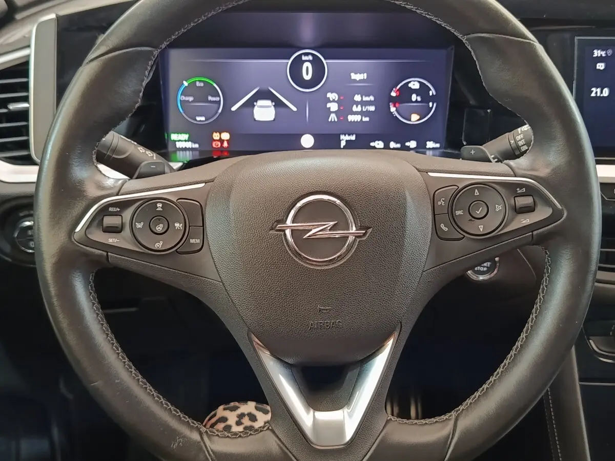 Vue rapprochée du volant cuir et alu multifonctions de l’Opel Grandland Hybride 225 ch, avec tableau de bord numérique.