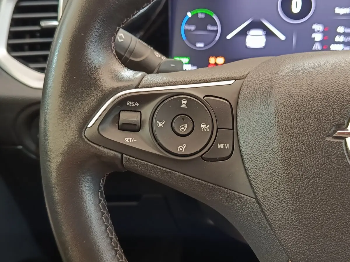 Gros plan sur le volant cuir et alu noir de l’Opel Grandland hybride 225 ch, avec commandes multifonctions visibles.