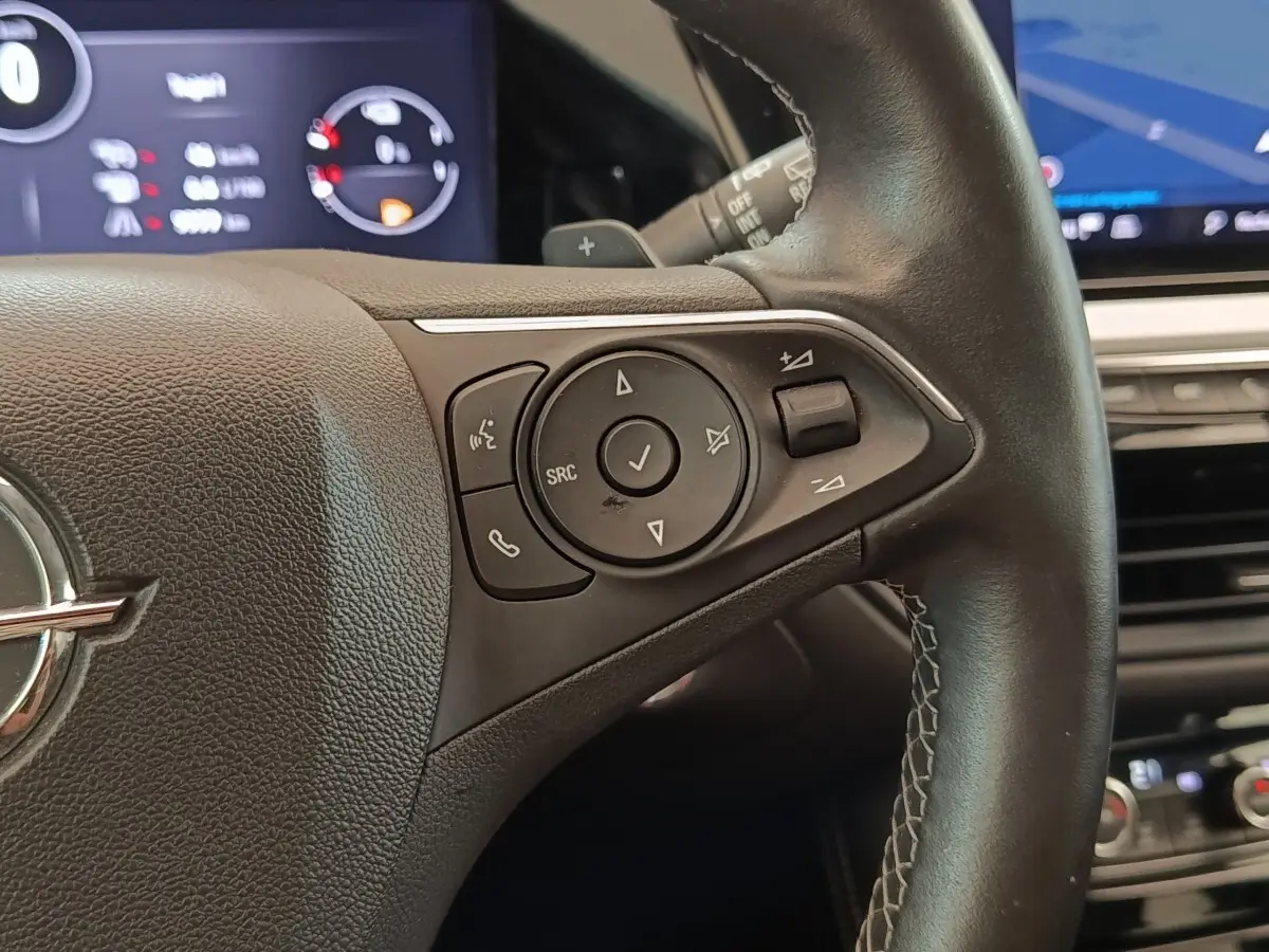 Gros plan sur le volant cuir et alu multifonctions de l’Opel Grandland hybride noir, avec commandes audio intégrées.
