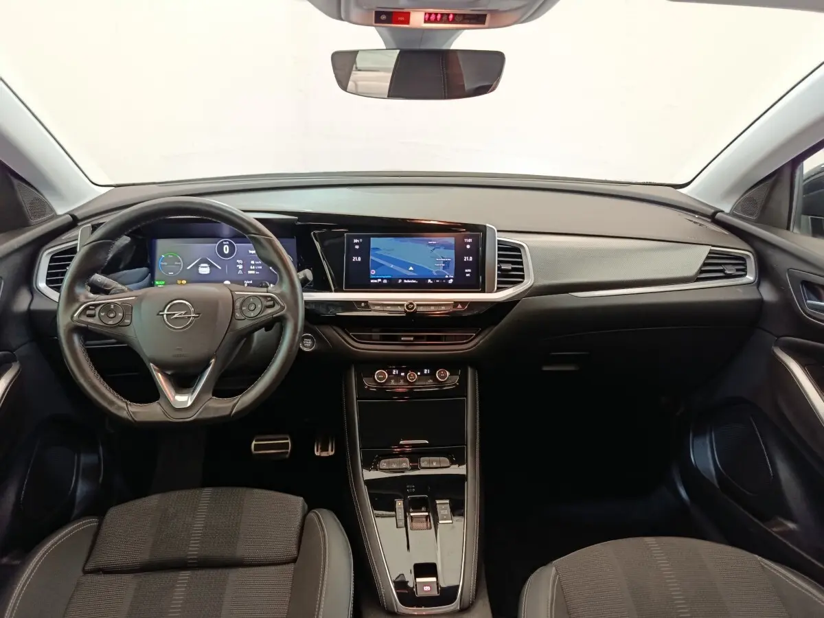 Vue intérieure avant de l'Opel Grandland Hybride 225 ch, tableau de bord moderne avec écran tactile et volant cuir multifonctions.