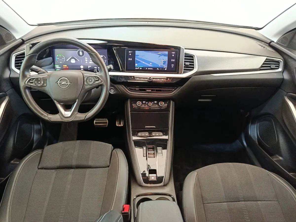 Vue intérieure avant de l’Opel Grandland hybride 2023, tableau de bord noir avec écran tactile central et volant cuir multifonctions.