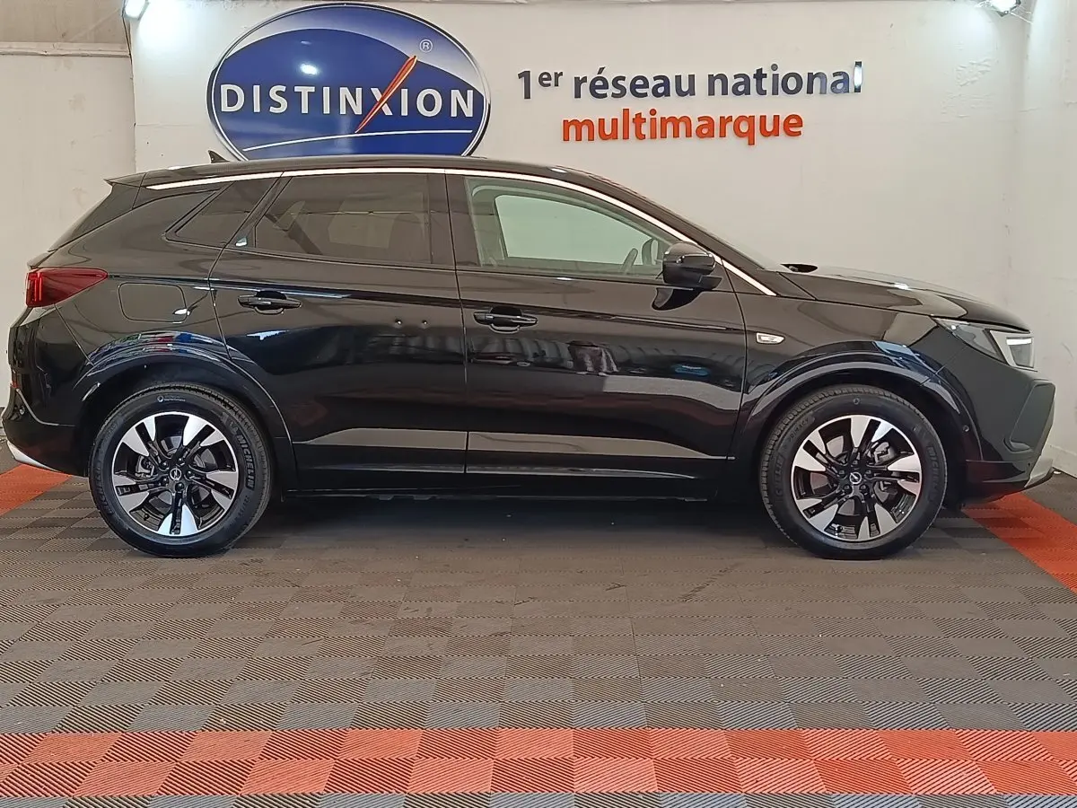Opel Grandland hybride 225 ch noir en profil droit, jantes alliage bicolores et toit avec spoiler de toit.