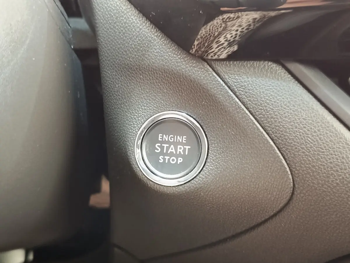 Gros plan sur le bouton démarrage moteur noir entouré de chrome dans l'habitacle d'un Opel Grandland noir 2023.