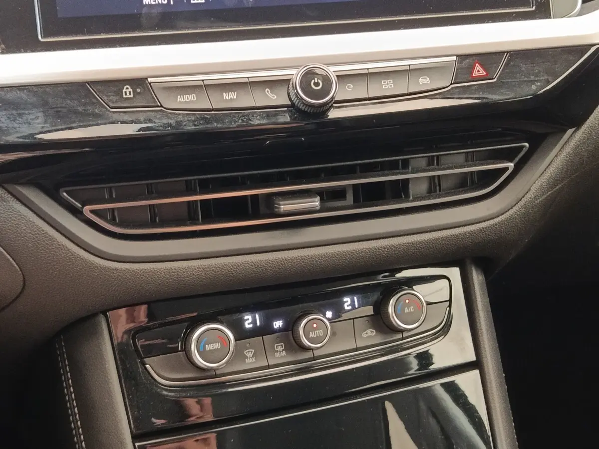 Vue rapprochée de la console centrale noire de l’Opel Grandland 2023, avec commandes climatisation digitale et ventilation.