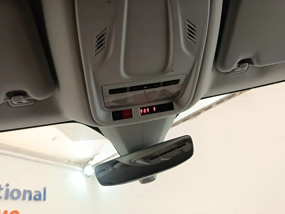 Vue intérieure du plafond avant de l'Opel Grandland noir, montrant le miroir intérieur et les commandes SOS et éclairage.
