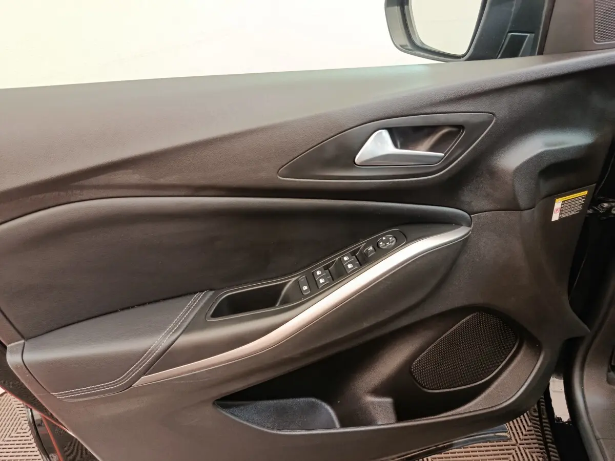 Vue intérieure côté gauche de la porte avant noire de l'Opel Grandland hybride avec commandes électriques et poignée alu.