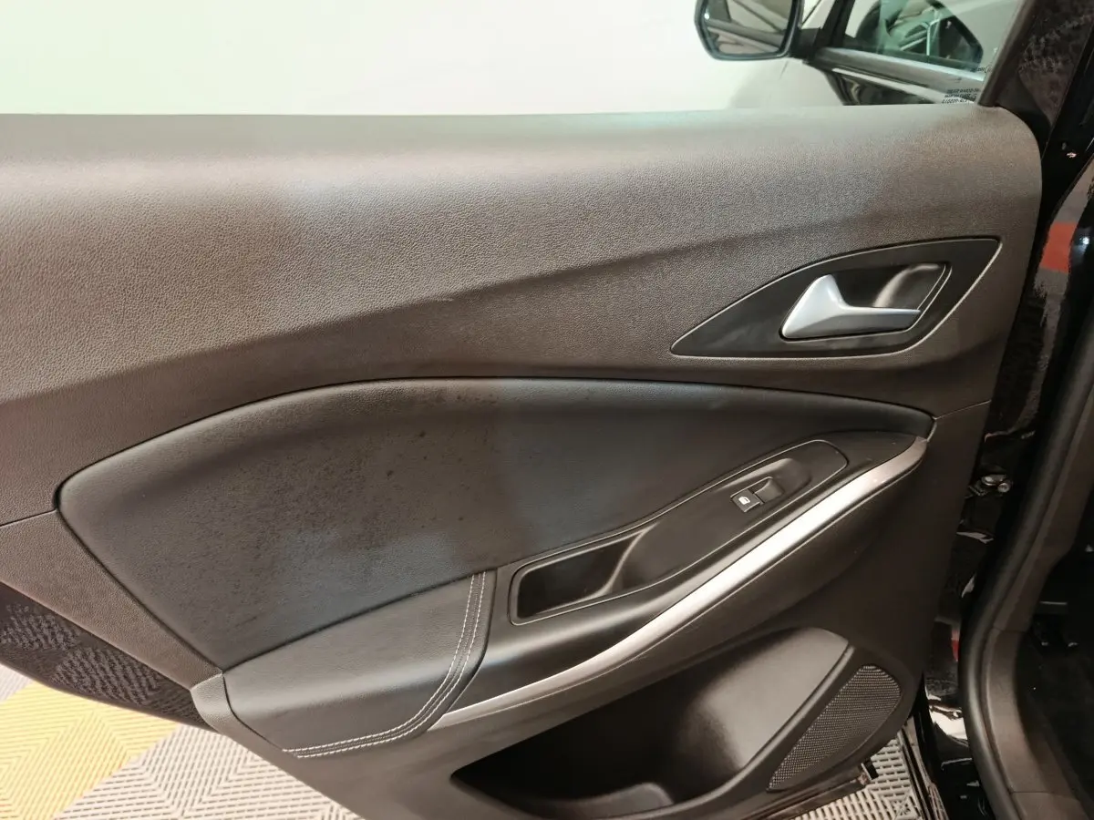 Vue rapprochée de la porte avant droite noire de l’Opel Grandland hybride 2023, avec poignée alu et commandes vitres.