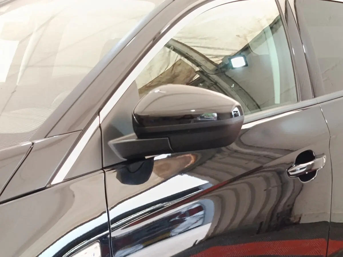 Gros plan sur le rétroviseur et la portière côté conducteur d’un Opel Grandland hybride noir brillant.
