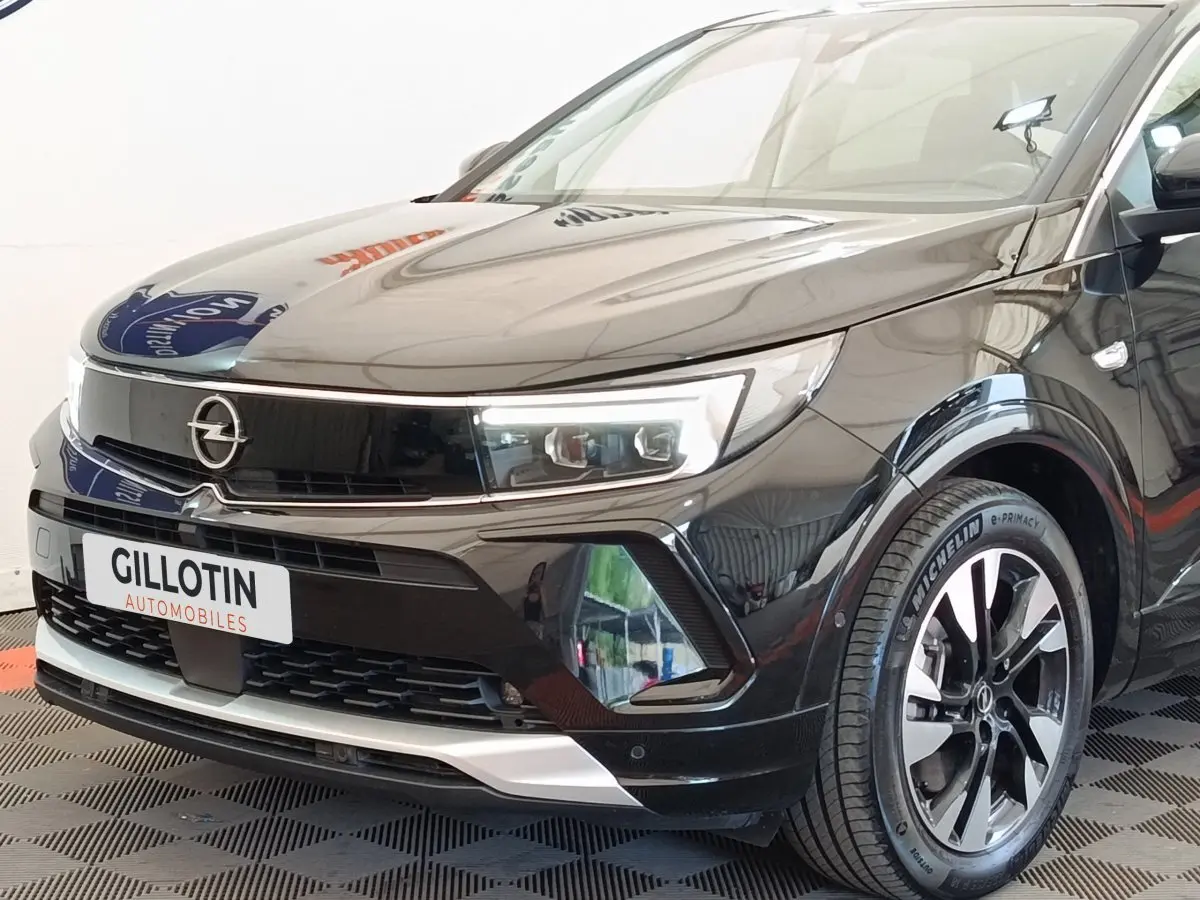 Vue 3/4 avant droit de l’Opel Grandland noir hybride 225 ch avec phares LED et jantes alliage distinctives.