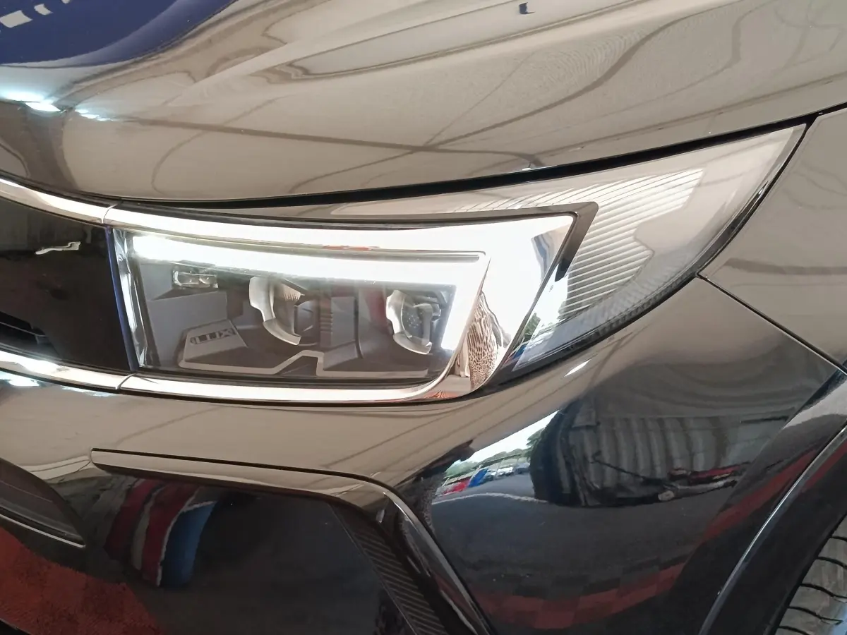 Gros plan sur le phare avant droit du SUV Opel Grandland noir brillant, soulignant ses lignes modernes et épurées.
