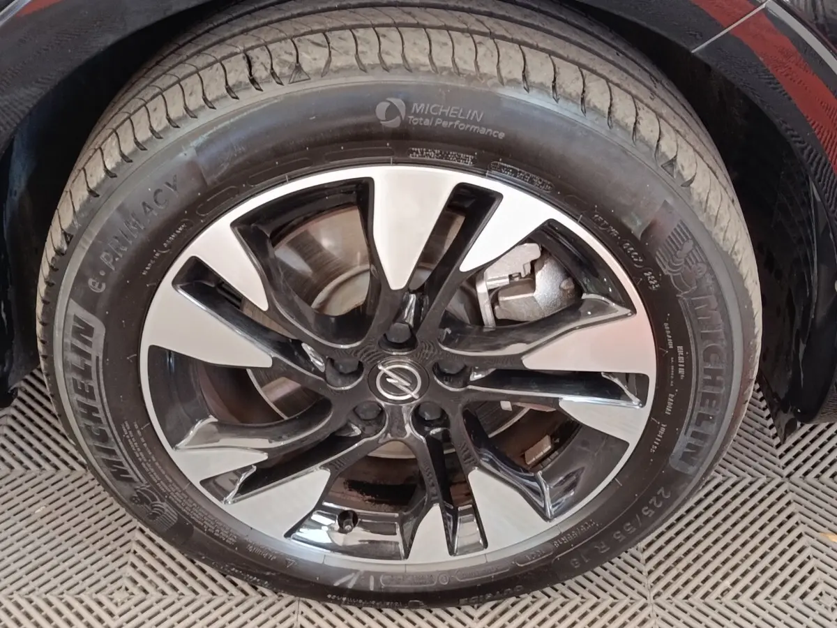 Gros plan sur la jante alu bicolore et pneu Michelin du côté avant droit d’un Opel Grandland noir hybride 2023.