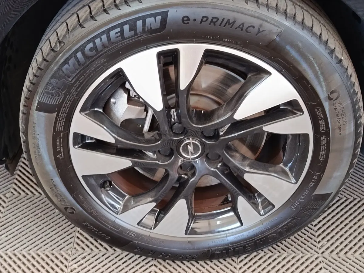 Gros plan sur la jante alliage bicolore noire et argentée d’un Opel Grandland hybride 2023, pneu Michelin visible.