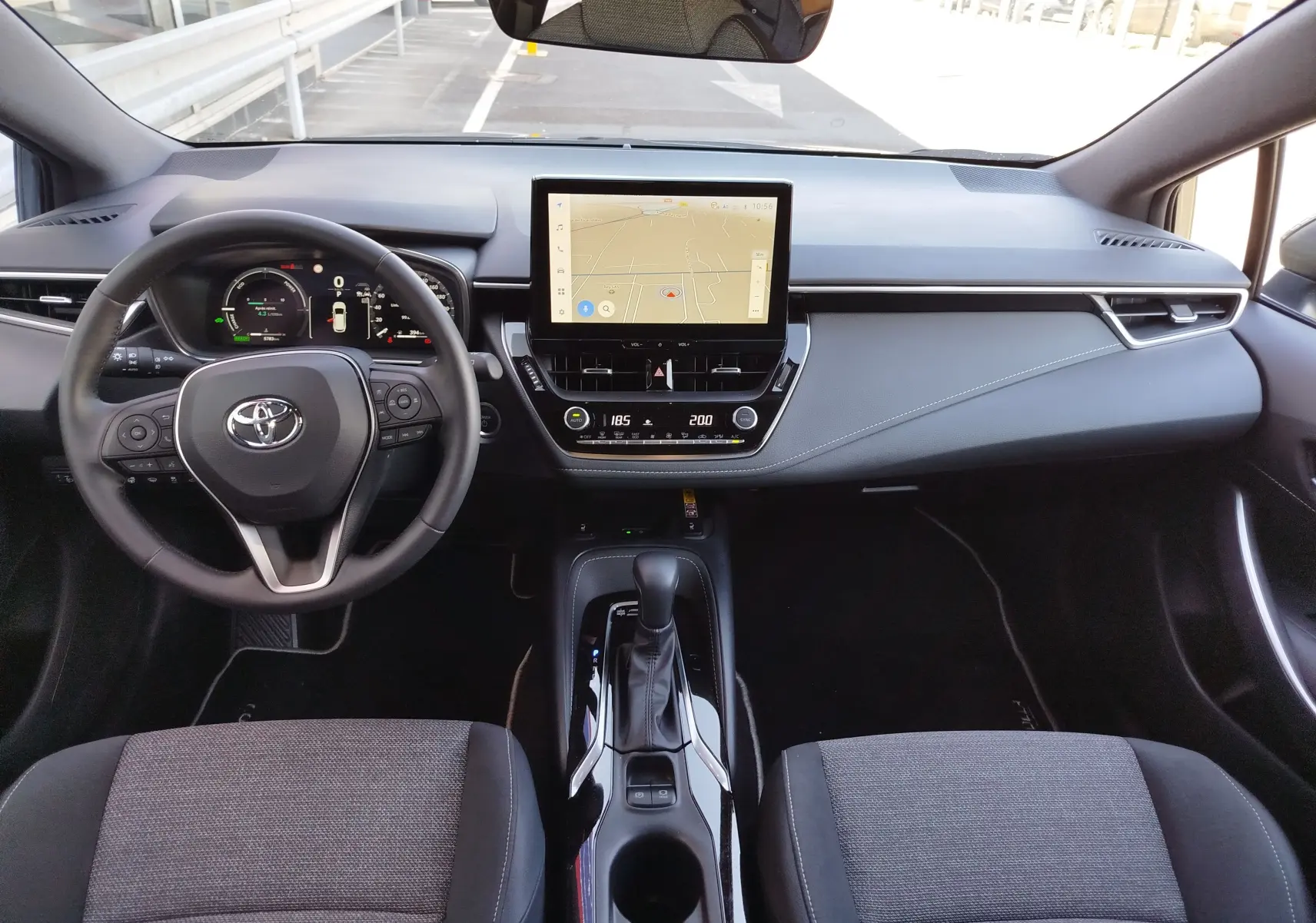 Vue intérieure frontale du tableau de bord et console centrale de la Toyota Corolla Touring Sport gris Atlas avec écran tactile et volant multifonction.