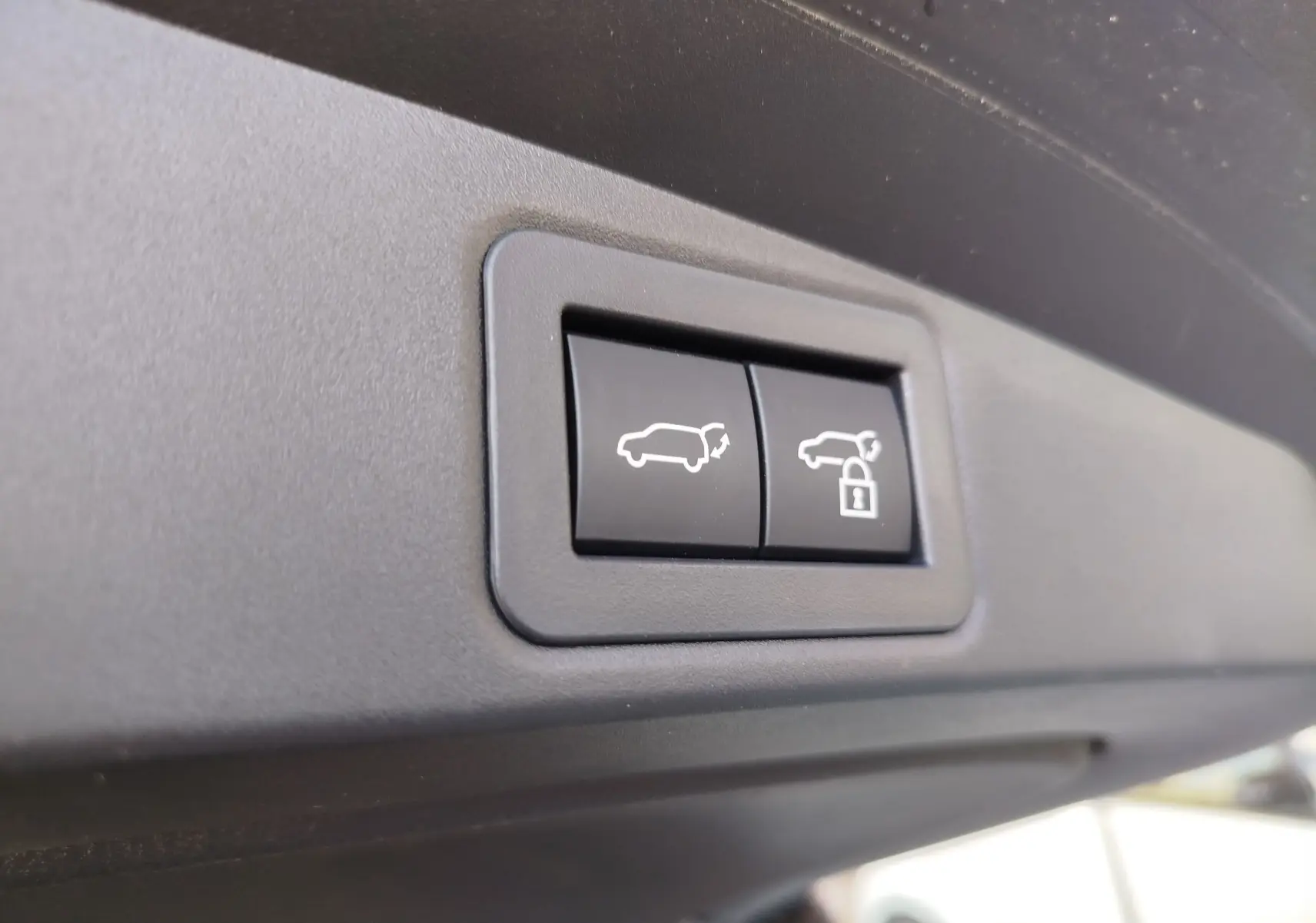Gros plan sur les boutons d'ouverture et de verrouillage du hayon du Toyota Corolla Touring Sport gris Atlas 2026.