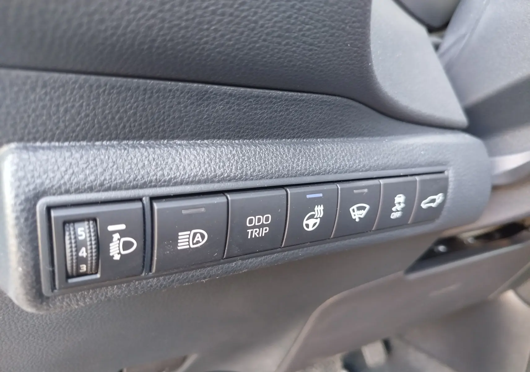 Gros plan sur les commandes latérales noires du tableau de bord de la Toyota Corolla Touring Sport gris Atlas.