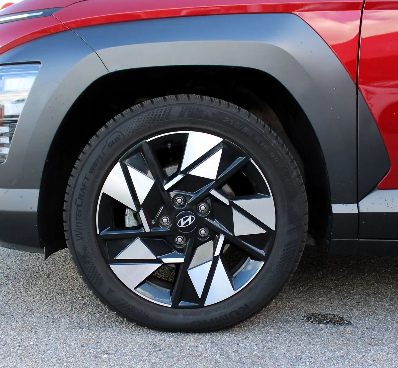 Gros plan sur la roue avant gauche du Hyundai Kona 2024 rouge Ultimate Metal avec jante alliage noire et argent.