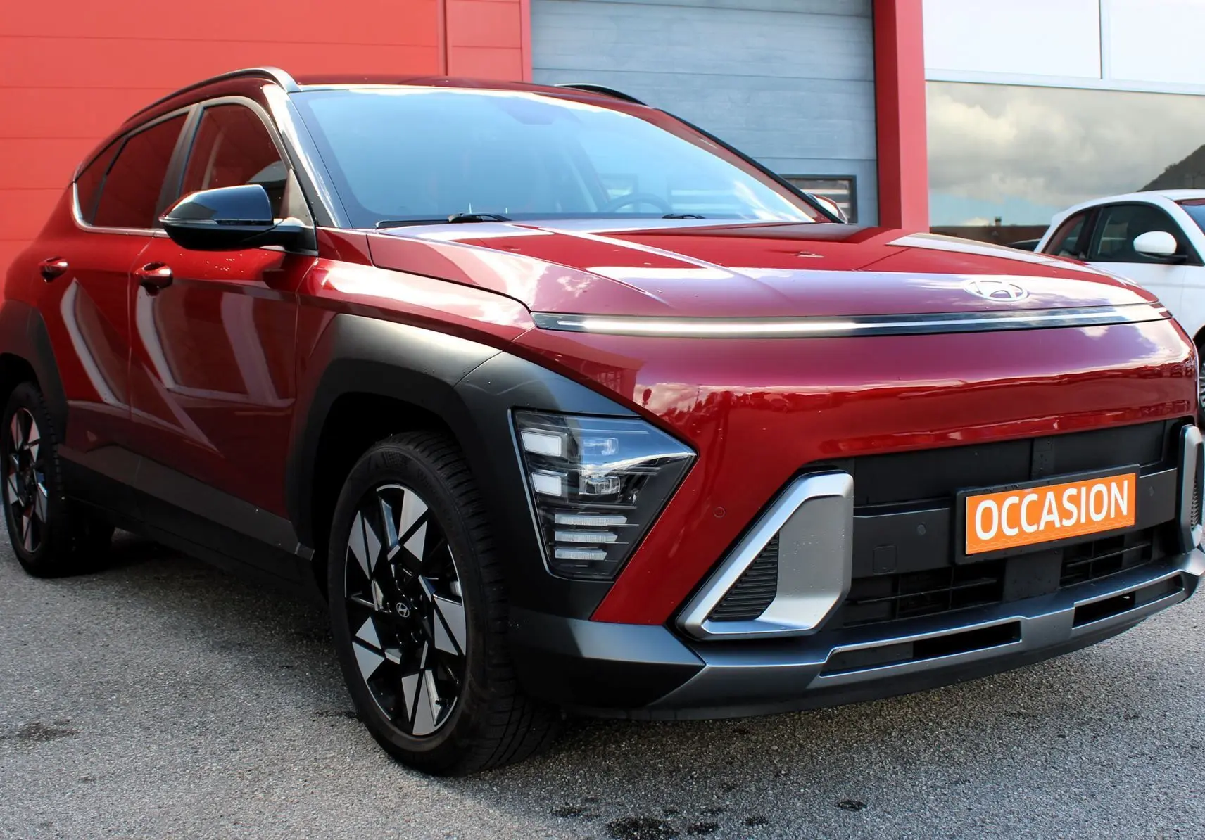 Hyundai Kona 2024 rouge Ultimate Metal vue 3/4 avant gauche avec détails noirs et jantes bicolores.