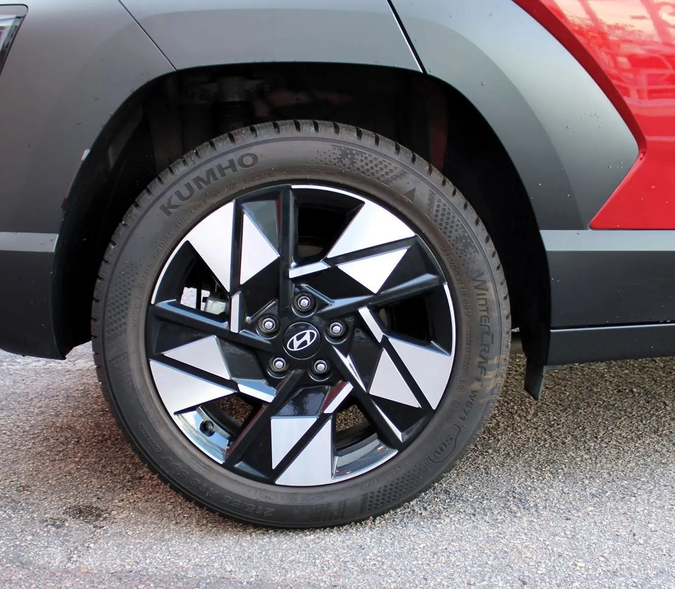 Gros plan sur la roue avant droite du Hyundai Kona 2024 rouge Ultimate Metal avec jante alliage noire et argentée.