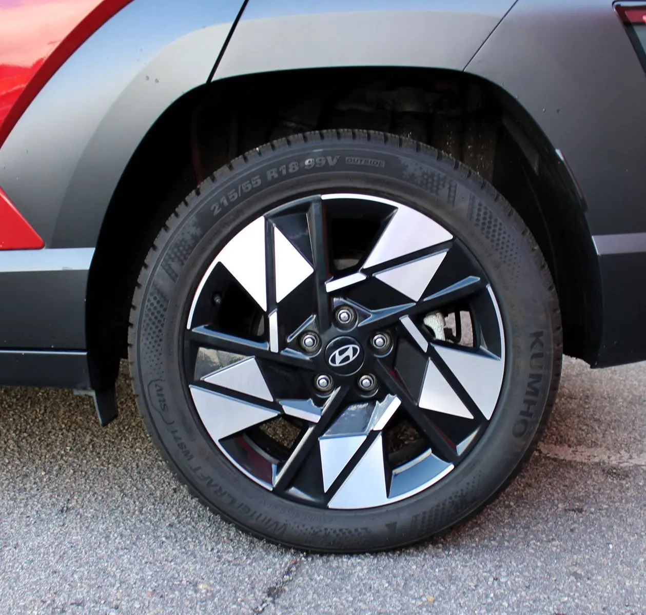Gros plan sur la roue arrière droite du Hyundai Kona 2024 rouge Ultimate Metal avec jante alliage noire et argentée.