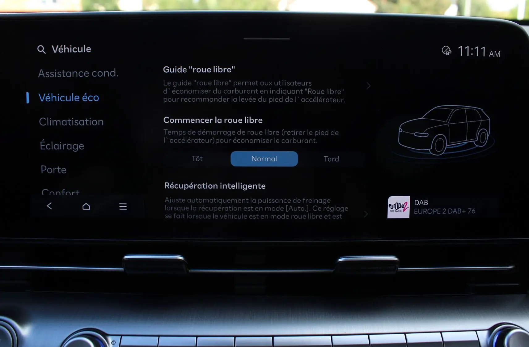 Écran tactile central du Hyundai Kona 2024 affichant les réglages du mode éco et guide "roue libre" en intérieur noir.