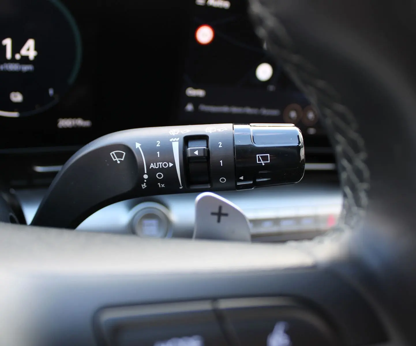 Gros plan sur la commande d’essuie-glace à gauche du volant dans l’habitacle du Hyundai Kona rouge 2024.