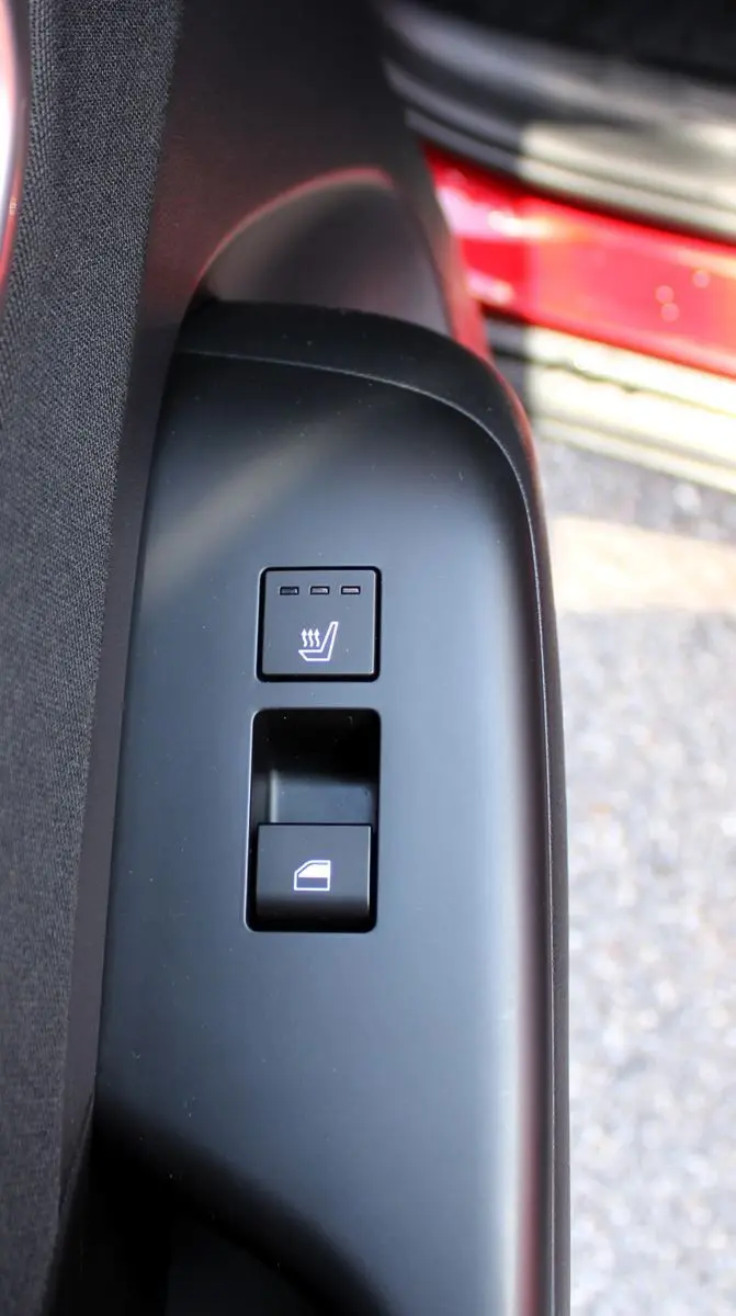 Gros plan sur les commandes de siège chauffant et de lève-vitre côté conducteur du Hyundai Kona rouge 2024.