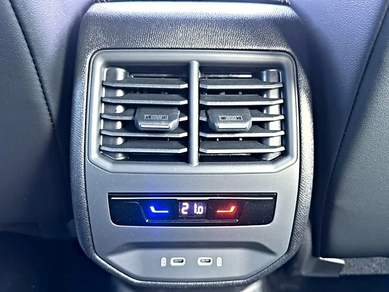 Vue rapprochée de la console arrière du CUPRA Formentor bleu fjord avec bouches d’aération et commande climatisation digitale.