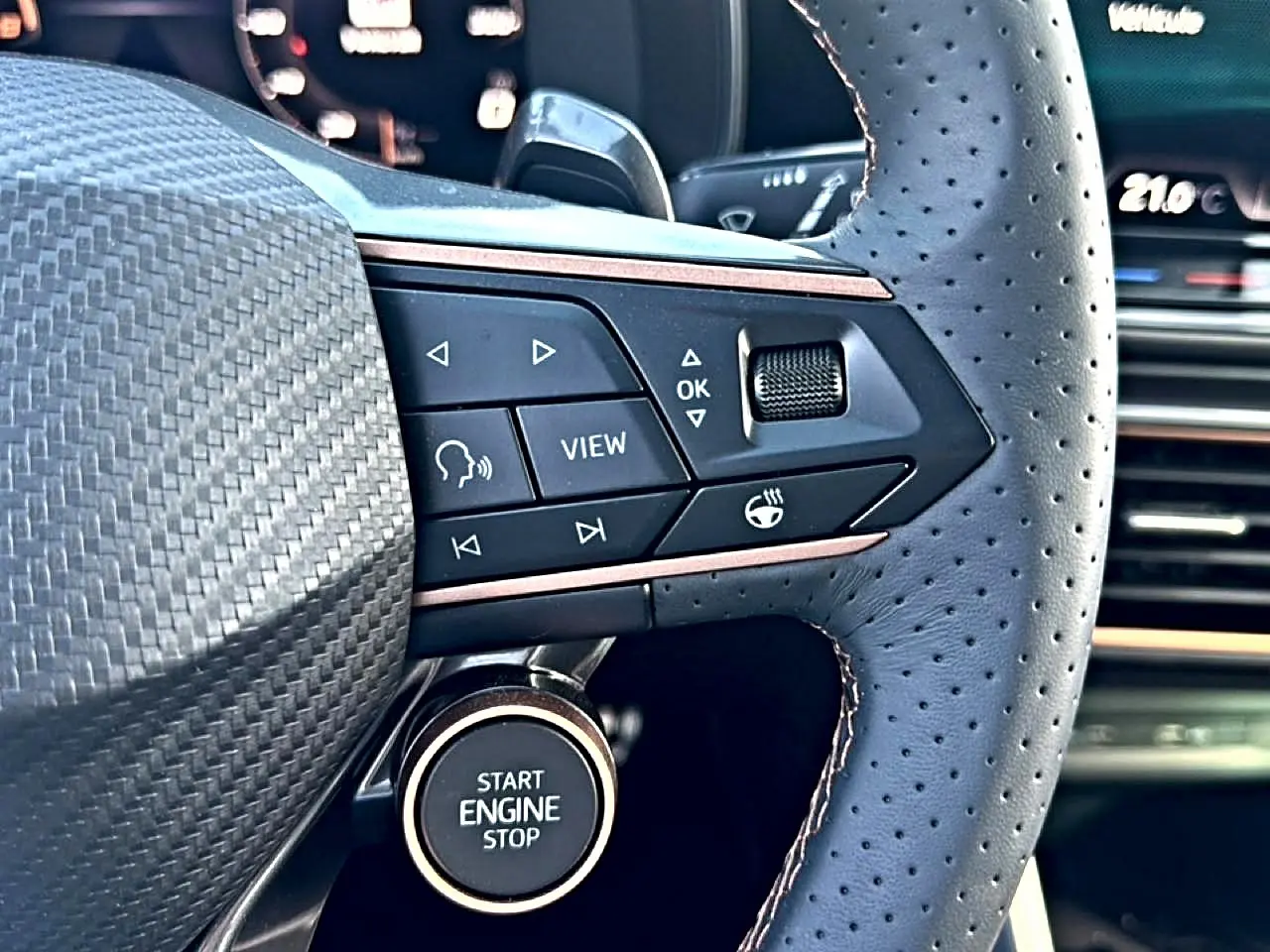 Gros plan sur le volant cuir perforé bleu fjord de la CUPRA Formentor 1.5 etsi hybrid avec commandes multifonctions et bouton start/stop.