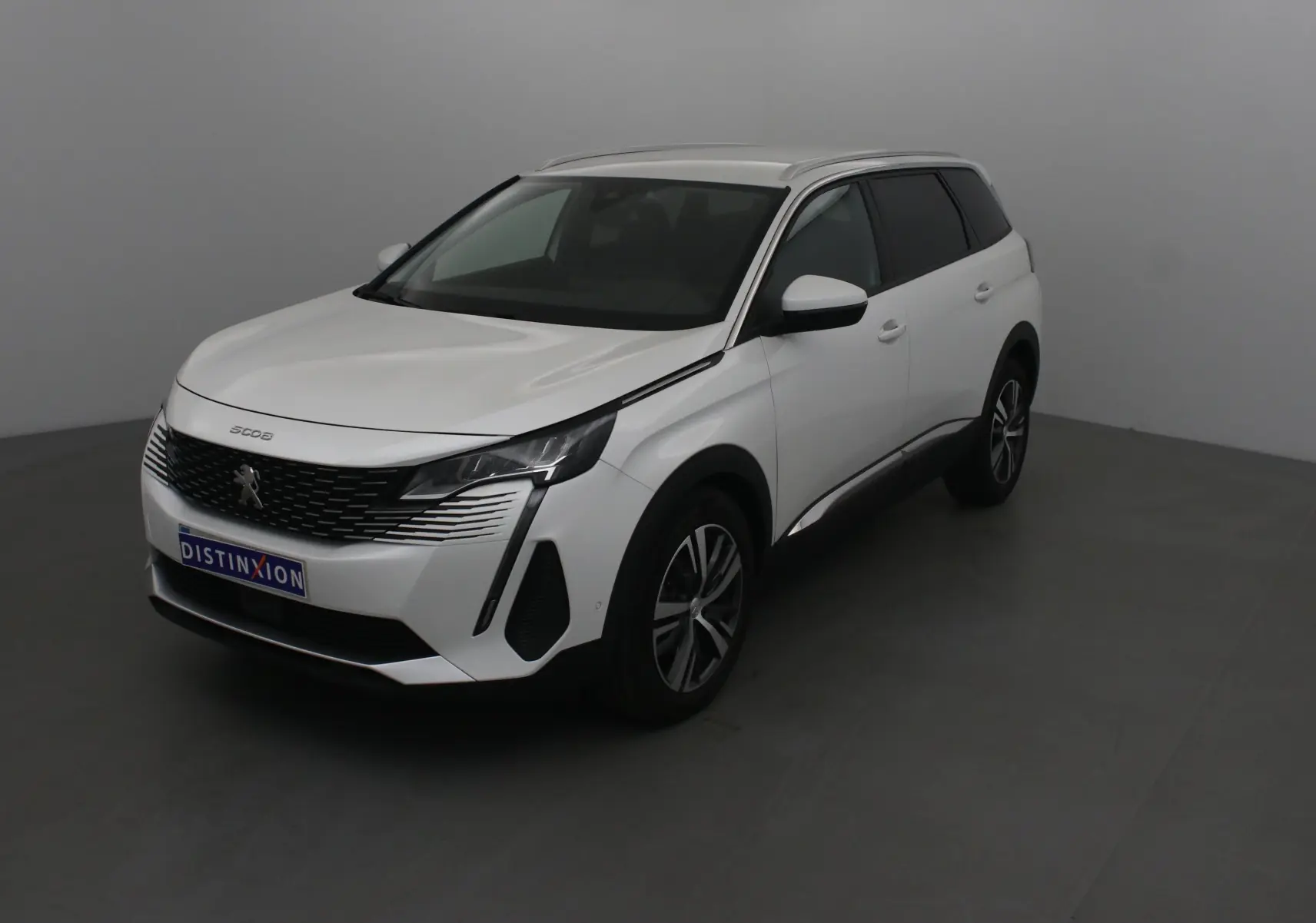 Peugeot 5008 blanc nacré en 3/4 avant droit, avec calandre distinctive et jantes alliage 18 pouces.