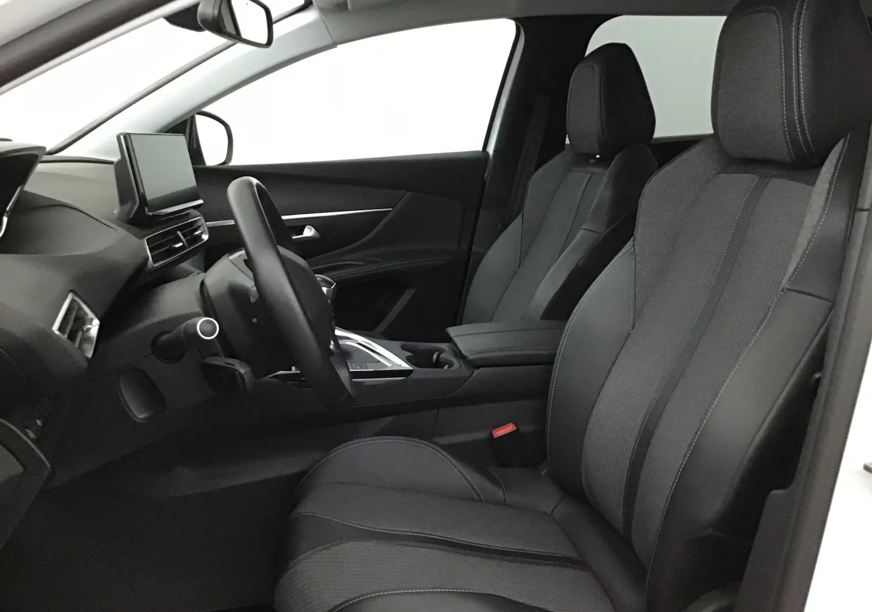 Vue intérieure côté conducteur du Peugeot 5008 2021, sièges en cuir noir avec surpiqûres blanches et tableau de bord moderne.