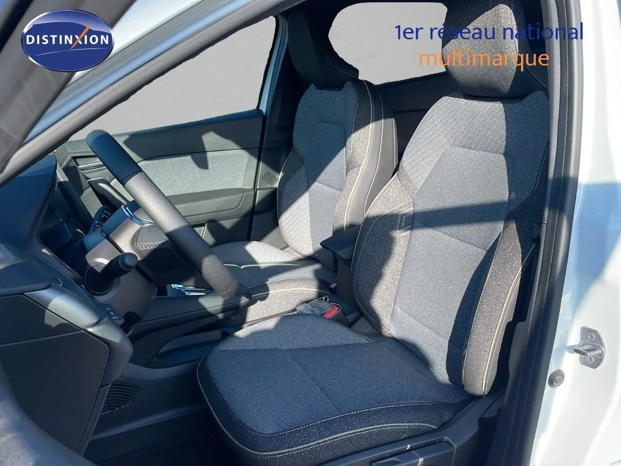 Vue intérieure côté conducteur du Renault Captur blanc nacré, sièges tissu gris avec surpiqûres claires.