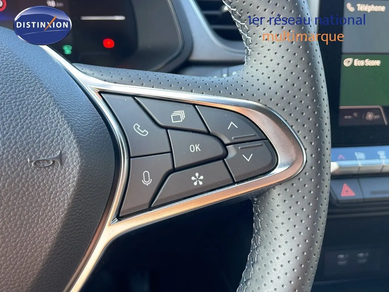 Gros plan sur les commandes au volant en cuir perforé du Renault Captur blanc nacré 2025, avec écran tactile en arrière-plan.