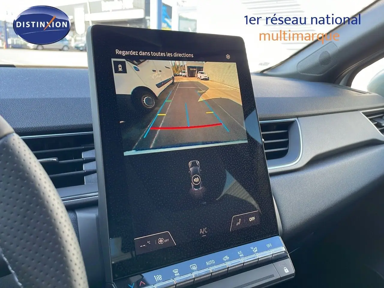 Vue intérieure du tableau de bord du Renault Captur blanc nacré, écran tactile affichant la caméra de recul en marche.