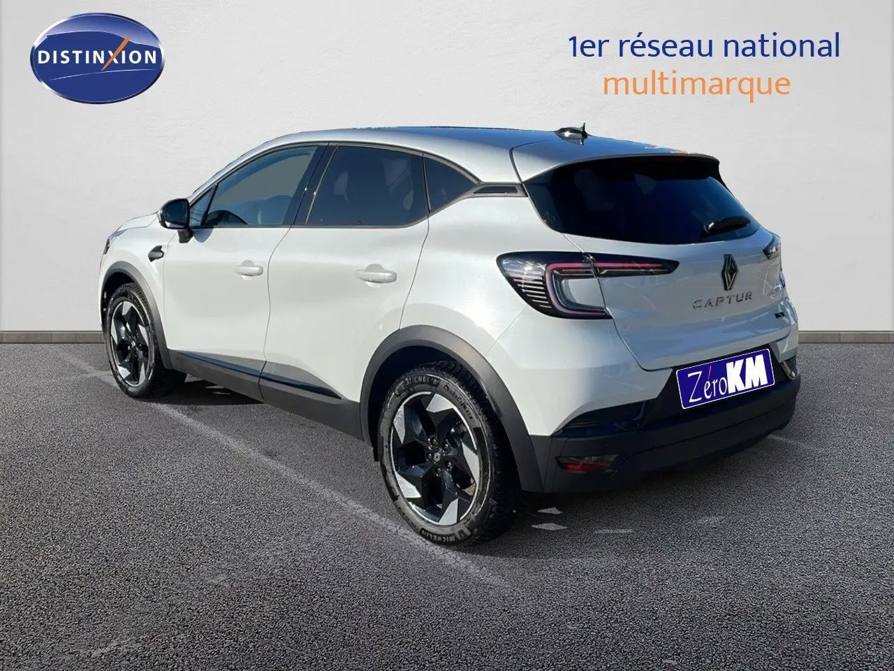 Vue 3/4 arrière droite d'un Renault Captur blanc nacré avec toit gris, jantes noires et feux LED distinctifs.