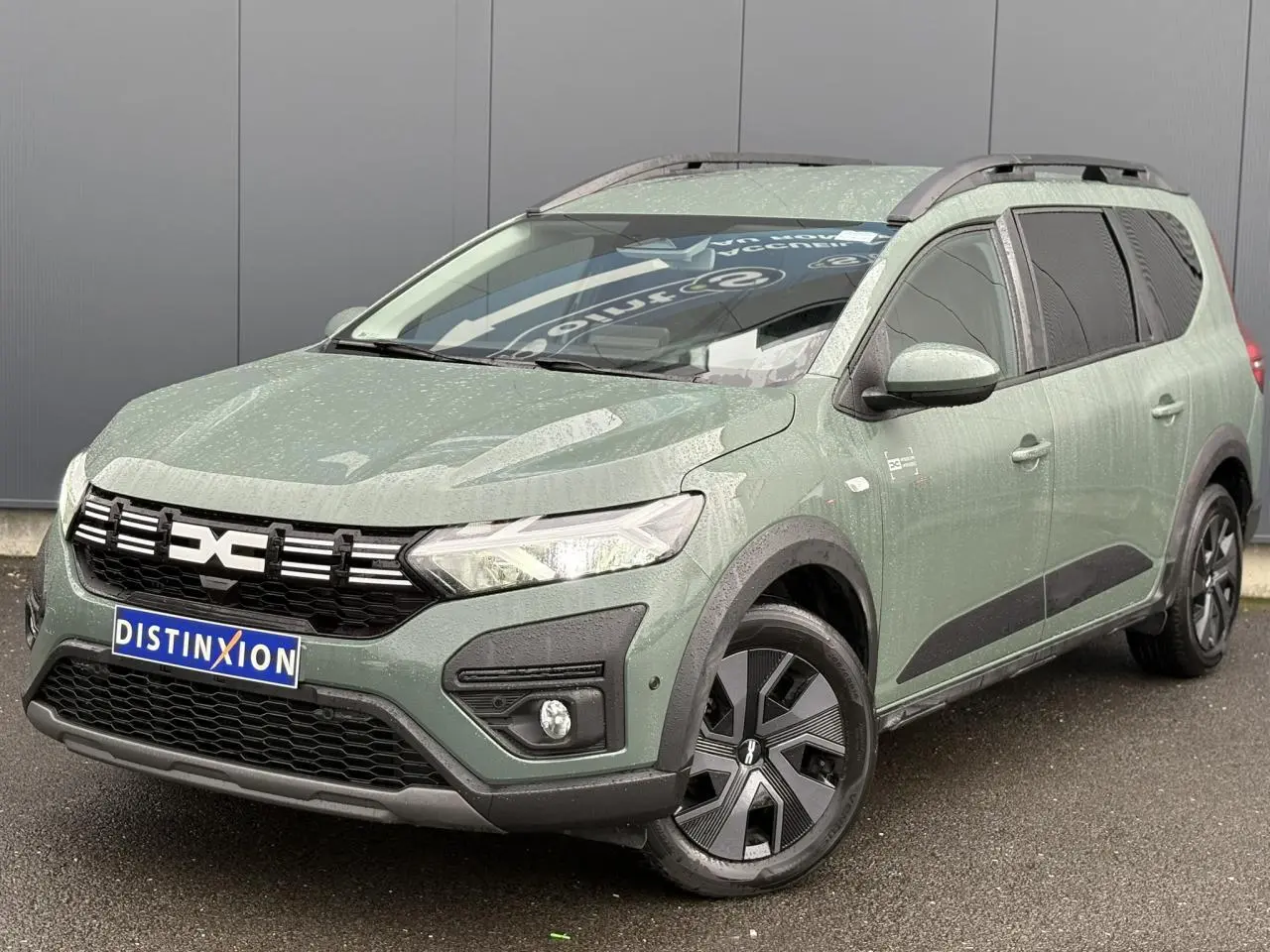 Dacia Jogger ECO-G 2025 kaki lichen en 3/4 avant droit avec barres de toit et jantes spécifiques.