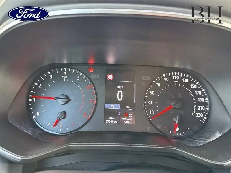 Tableau de bord de Renault Clio blanc 2020, affichage numérique central et compteurs analogiques en vue frontale rapprochée.