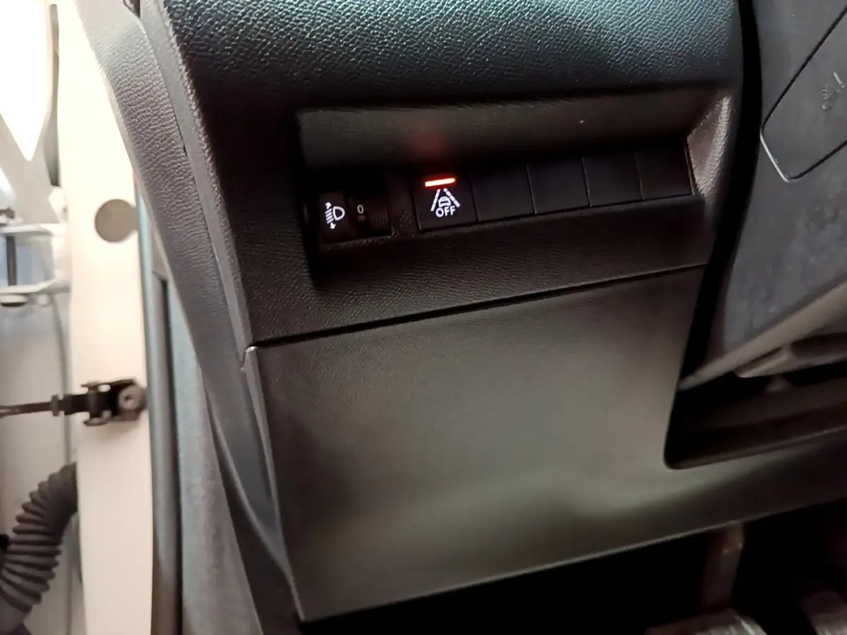 Détail du tableau de bord côté gauche d’une Peugeot 208 blanche, avec bouton d’alerte de franchissement de ligne activé.