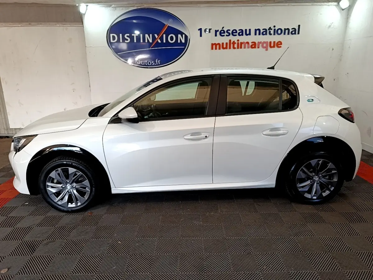 Peugeot 208 électrique blanche vue de profil côté gauche, avec jantes alliage et logo Distinxion en arrière-plan.