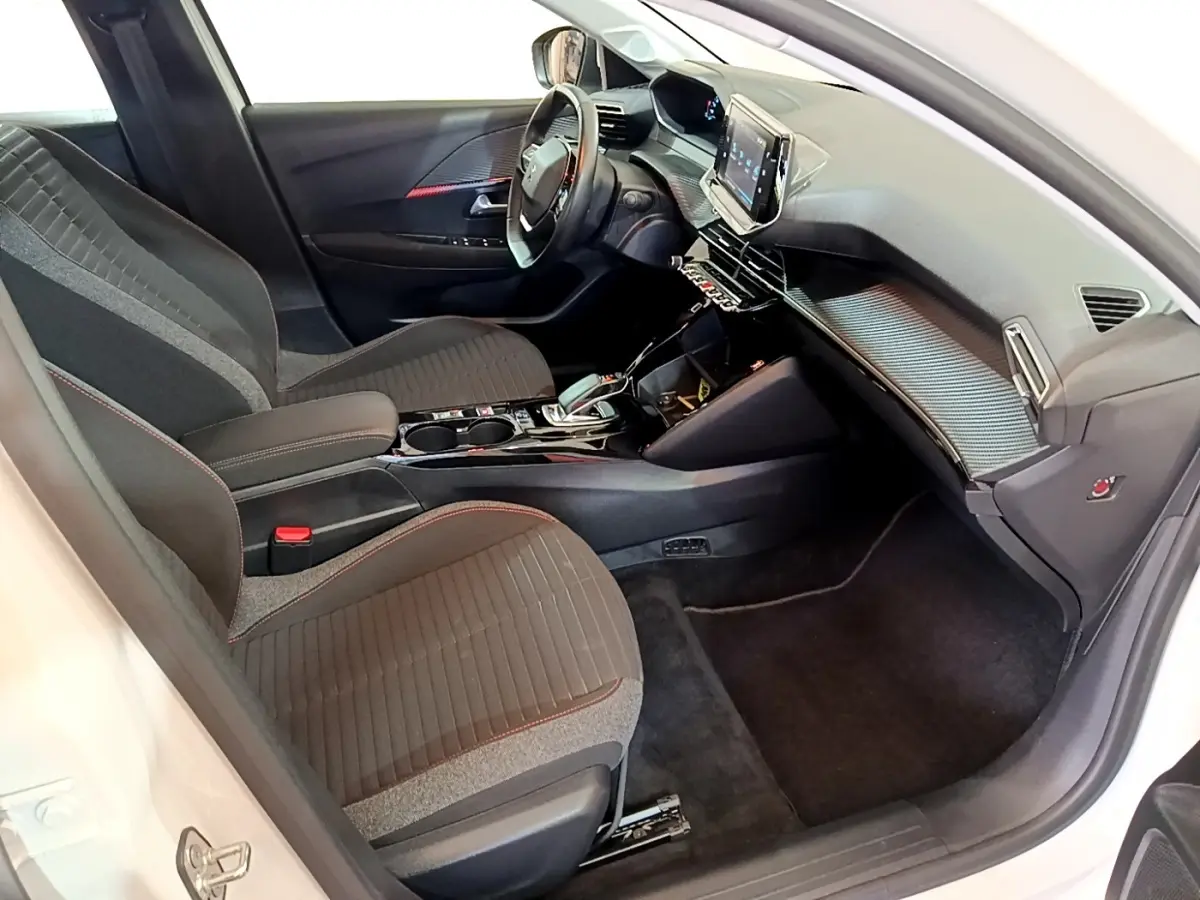 Vue intérieure côté conducteur de la Peugeot 208 Electrique Active Business blanche, avec tableau de bord moderne et écran tactile.