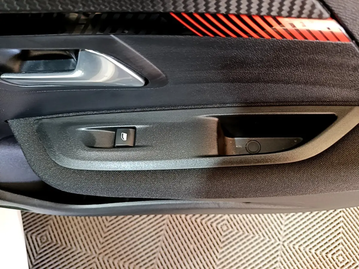 Gros plan sur la poignée intérieure et le bouton de lève-vitre côté conducteur d'une Peugeot 208 Electrique Active Business.