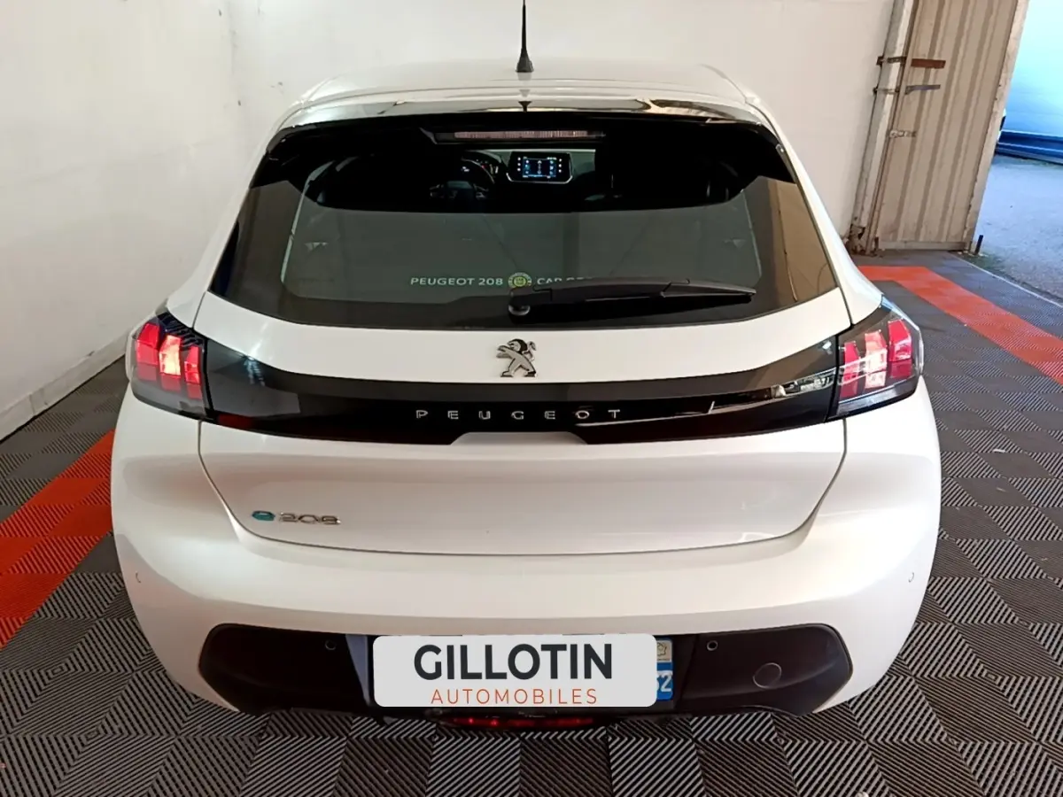 Vue arrière d'une Peugeot 208 électrique Active Business blanche, avec feux LED et bande noire distinctive sur le hayon.