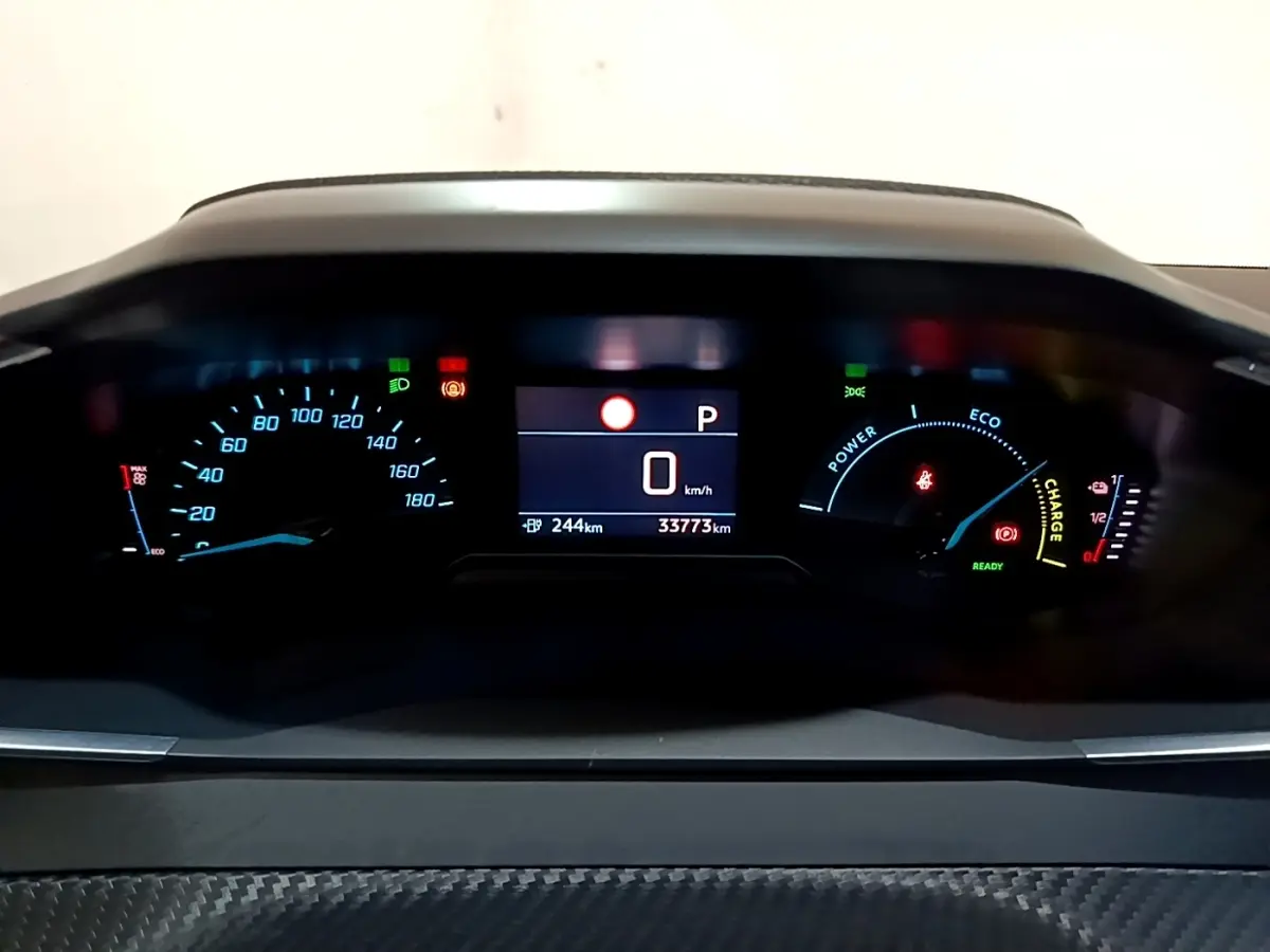 Vue rapprochée du tableau de bord numérique de la Peugeot 208 électrique, affichage vitesse, autonomie et indicateurs énergie.