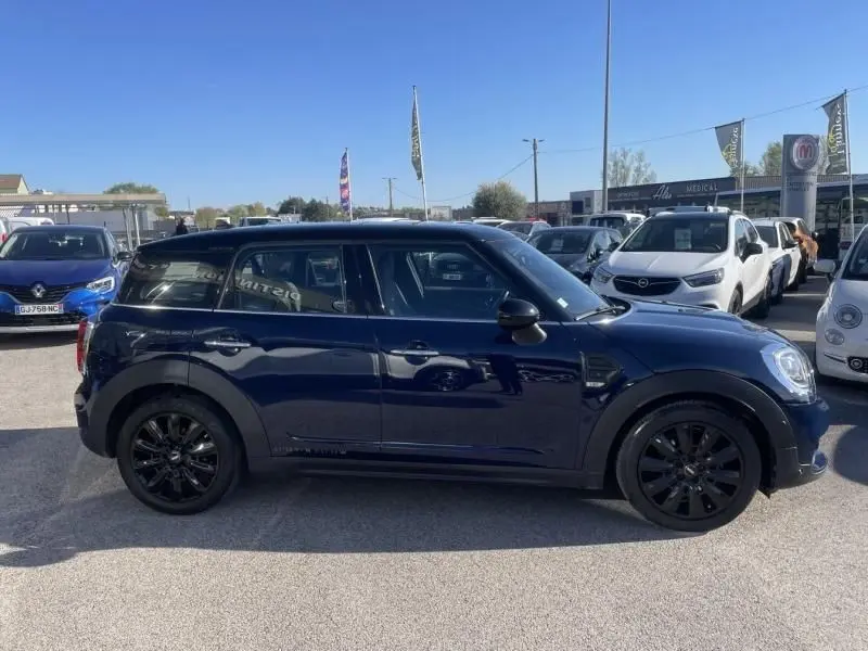 Vue de profil côté gauche d'une MINI Countryman Cooper D bleu foncé avec jantes noires, stationnée en extérieur.
