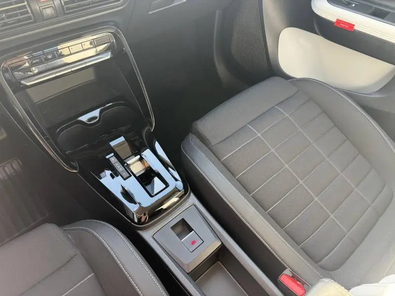 Vue intérieure rapprochée de la console centrale et siège avant droit en tissu noir de la Citroën C3 électrique 2025.