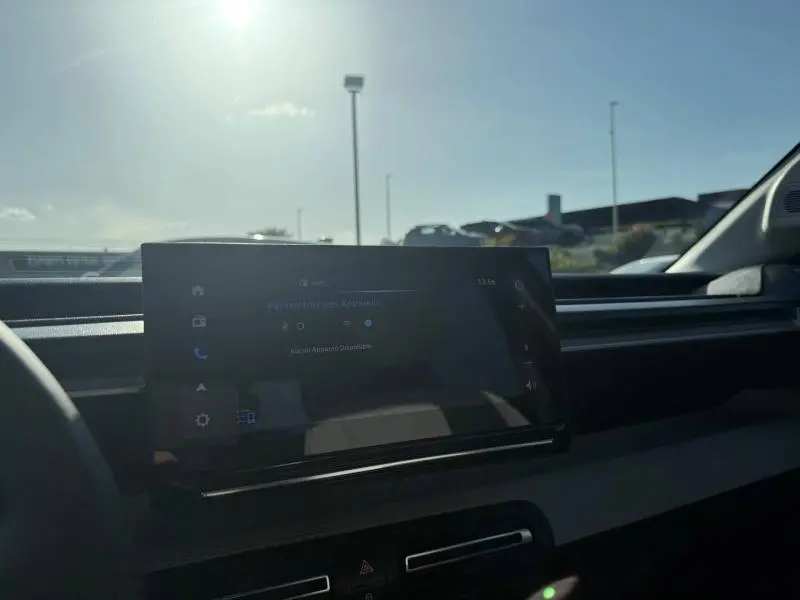 Vue intérieure de la Citroën C3 électrique 2025, écran tactile central avec tableau de bord noir sous lumière naturelle.