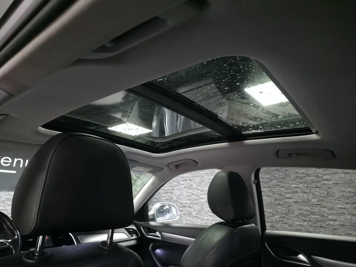 Vue intérieure de l'Audi Q3 2016 avec toit ouvrant panoramique et sièges en cuir noir.