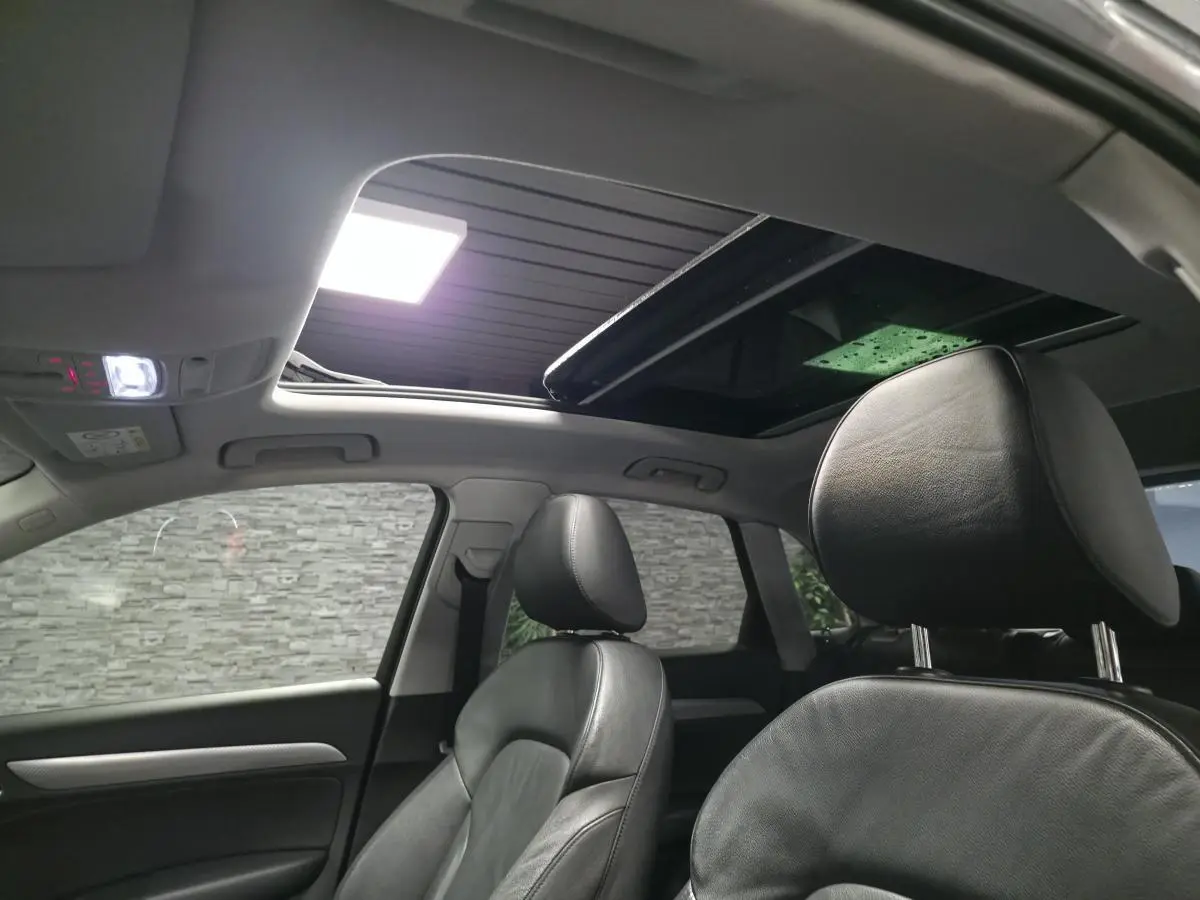 Vue intérieure avant droite de l'Audi Q3 2016 avec sellerie cuir noire et toit ouvrant panoramique ouvert.