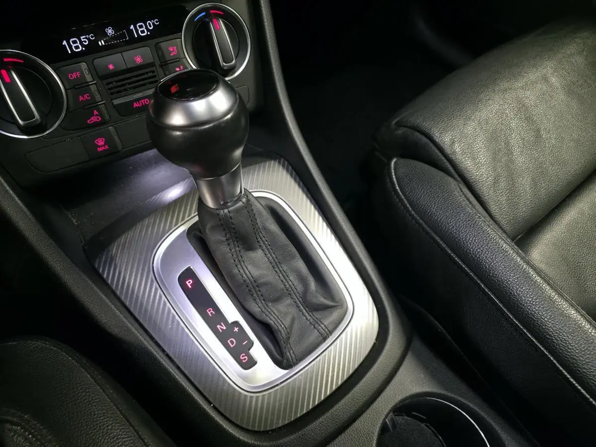 Gros plan sur la console centrale d’un Audi Q3 2016 avec levier de boîte automatique et sellerie cuir noire.