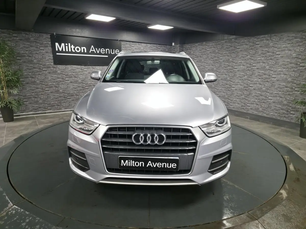 Audi Q3 gris métallisé vue de face, calandre Singleframe avec anneaux Audi et plaque Milton Avenue.