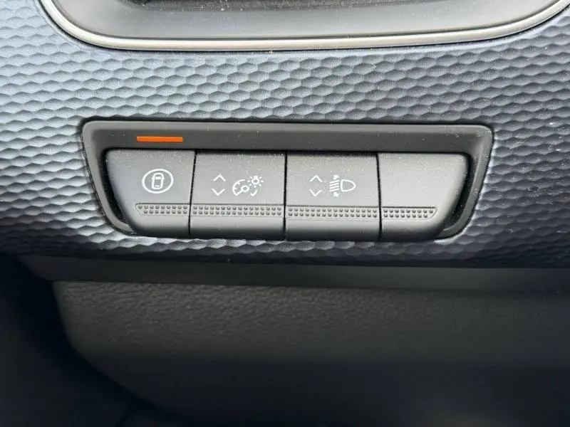 Gros plan sur les boutons de réglage d’éclairage et verrouillage, tableau de bord texturé noir du Renault Arkana blanc 2025.